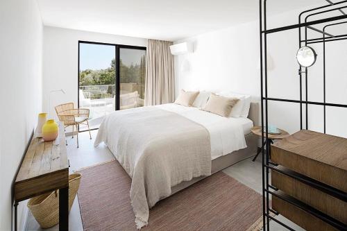 a white bedroom with a bed and a balcony at Casas de Carvoeiro by Sevencollection in Carvoeiro