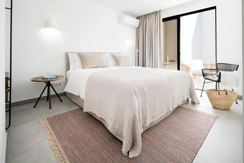 a white bedroom with a large bed with a rug at Casas de Carvoeiro by Sevencollection in Carvoeiro