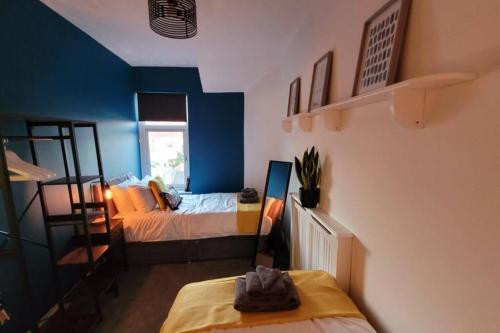1 dormitorio con cama y pared azul en Modern and Spacious 4 Bedroom House, Hot Tub, Wifi, Netflix, Parking en Paignton