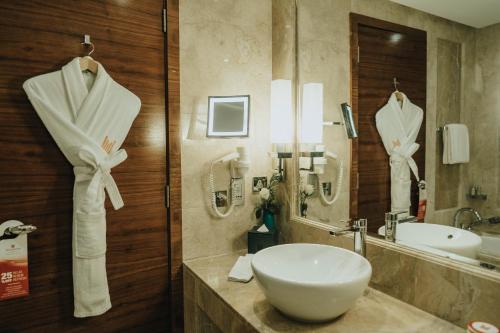 a bathroom with a white sink and a mirror at Grand Millennium Sulaimani in As Sulaymānīyah