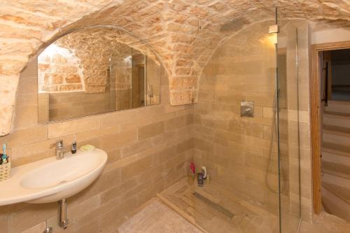 een badkamer met een wastafel en een glazen douche bij Casa Amahoro in Ostuni