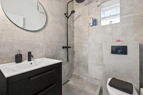 a bathroom with a sink and a shower with a mirror at Odinn Reykjavik Odinsgata Apartments in Reykjavík