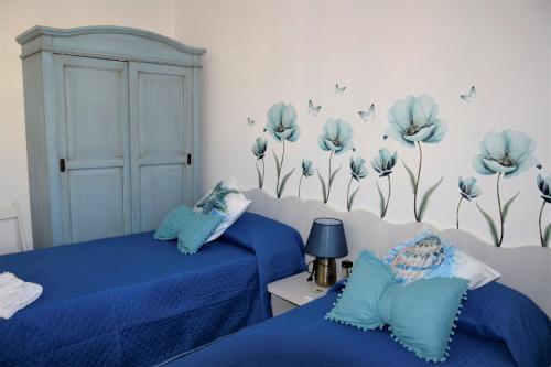 a bedroom with two beds and blue flowers on the wall at Pozzo Antico Apartments in San Vito lo Capo