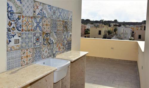 a bathroom with a tub and a tile wall at Pozzo Antico Apartments in San Vito lo Capo
