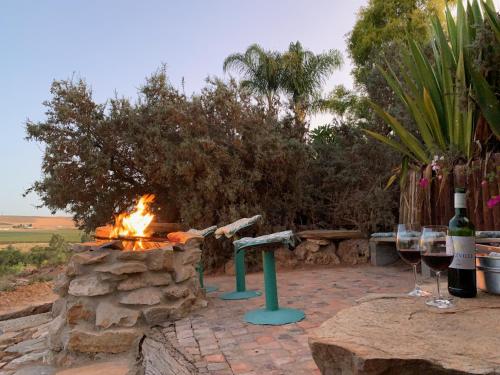 a fire pit with two glasses of wine and wine bottles at Melkboomsdrift Guest House & Conference Centre in Vredendal