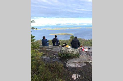 a group of people sitting on a rock looking out at the ocean at Kolin Pikkukolo - Saunallinen studiohuoneisto in Kolinkylä