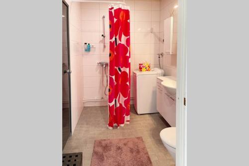 łazienka z czerwoną zasłoną prysznicową i toaletą w obiekcie Saunallinen huoneisto Kolilla w mieście Kolinkylä
