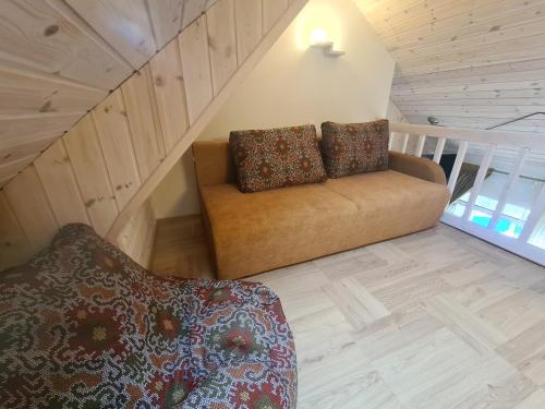 a couch with two pillows sitting in a room at Čiki puki apartamentai Pienės pūkas in Palanga