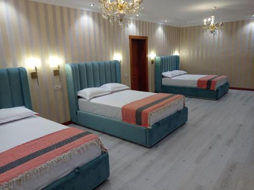 three beds in a hotel room with a chandelier at Comfortable Home Stay in Termiz