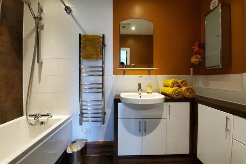 Un baño con lavabo, espejo y bañera. en The Riverside at Woodsmill Quay with parking, en York