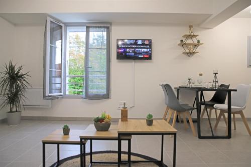 un soggiorno con tavoli e TV a parete di #Cosy Moments By Eauz'Homes - WiFi-Netflix a Eauze