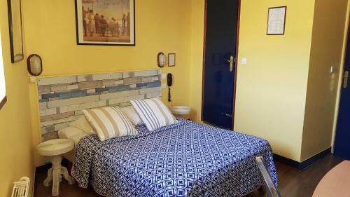a bedroom with a bed with a blue and white comforter at Hotel Vent d'Ouest in Fécamp