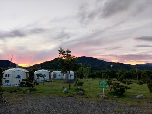 a couple of white tents in a field with a sunset at 枋山六號 in Fangshan