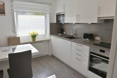 een keuken met witte kasten en een tafel en een raam bij Moderne,helle und ruhige Wohnung zur Alleinnutzung in Mindelheim