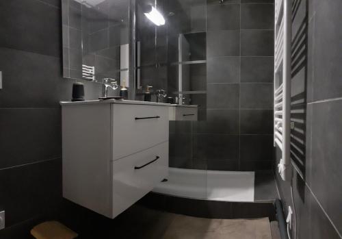 een badkamer met een witte wastafel en een spiegel bij Appartement refait à neuf 40m2, Cauterets Centre in Cauterets