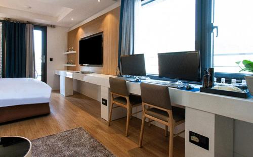 a hotel room with a desk with two monitors and a bed at Golden Hotel Incheon in Incheon