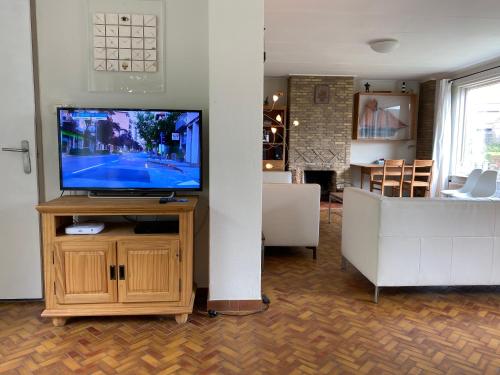 a living room with a television on a wooden stand at Kapiteinshuis Breskens in Breskens
