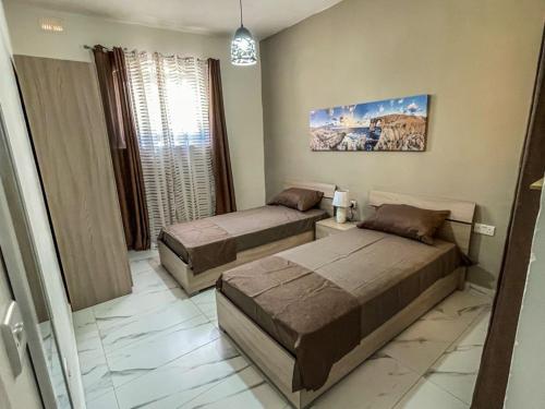 a bedroom with two beds and a window at Sun Sea Living Gozo in Xlendi