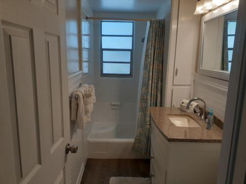 baño con bañera, lavabo y ventana en Turtle Crawl Inn - Longboat Key, en Longboat Key