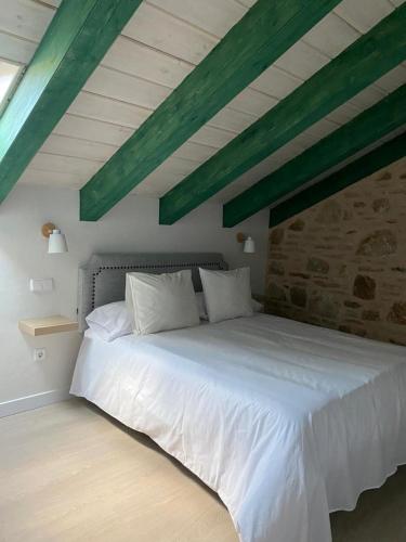 a bedroom with a white bed with a stone wall at EL PAJAR DE LEONOR in Horcajuelo de la Sierra