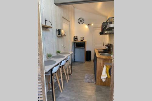 une cuisine avec des lavabos et une rangée de tabourets de bar dans l'établissement L'atelier, dépendance de charme, Ste Mère Église, à Sainte-Mère-Église