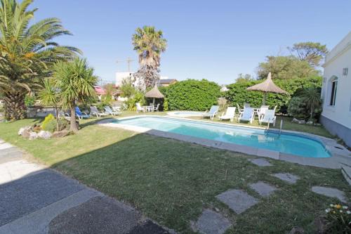 a swimming pool in a yard with chairs and trees at Hotel Mesón Do Vento in Piriápolis