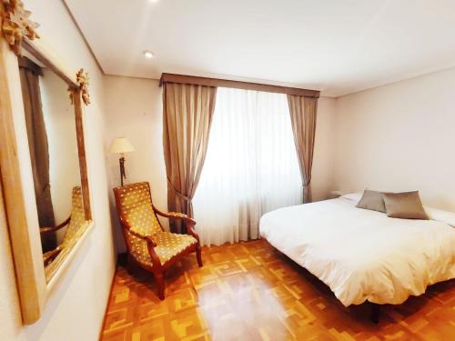 a bedroom with a bed and a chair and a window at Apartamento turístico San Juan in Pamplona
