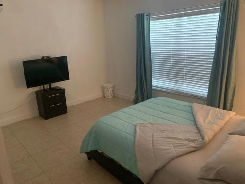 1 dormitorio con 1 cama, TV y ventana en Miami guest suite by airport, en Miami