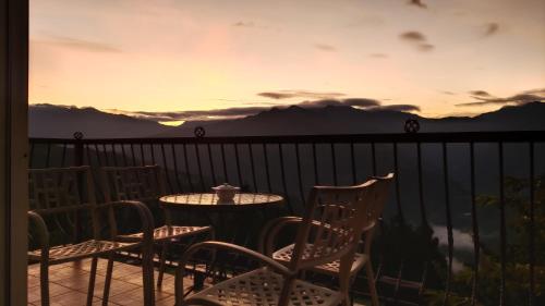 a table and chairs on a balcony with a sunset at Qingjing Baiyun Resort in Renai