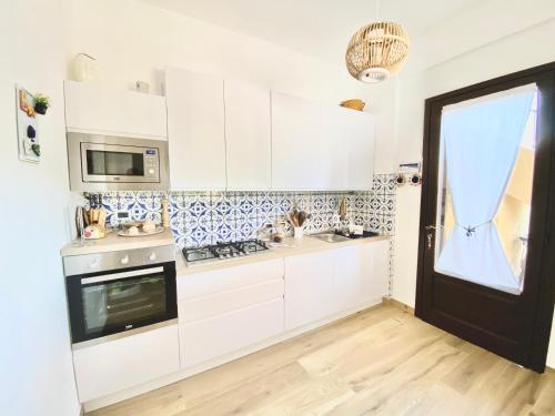a kitchen with white cabinets and a black door at ACasammare Apartment in Marsala