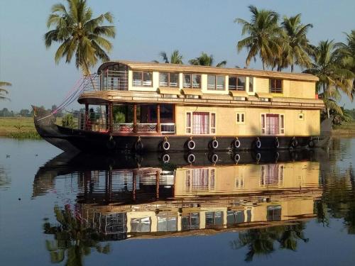 a boat on the water with palm trees in the background at Marari houseboat in Mararikulam