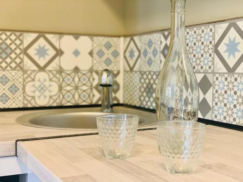 una botella y un vaso en una encimera con fregadero en Marseille 6ème Vauban élégant T3 6 couchages 2 chambres, en Marsella