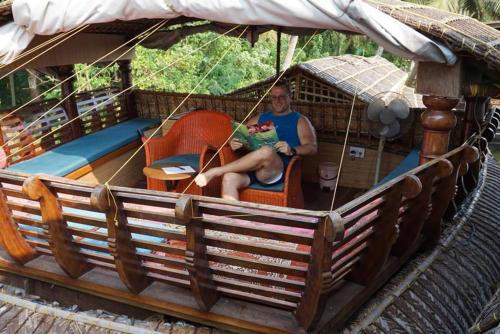 a man sitting in a swing in a boat at Sreekrishna Houseboat in Kumarakom