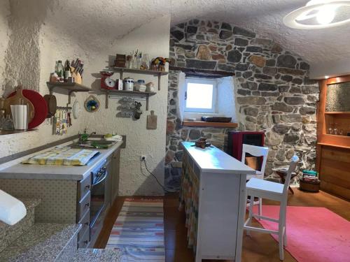 una cocina con una pared de piedra con una encimera y una mesa en Appartamento immerso nel cuore del parco dell Adamello, en Cimbergo