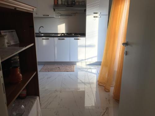 a kitchen with white cabinets and a tile floor at Camere in appartamento condiviso, vista sulla città in Udine