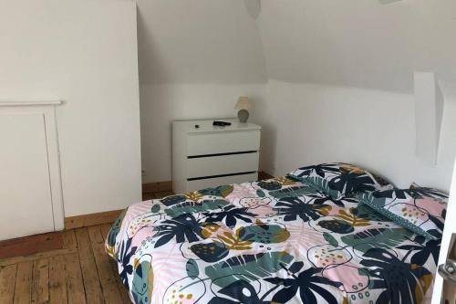 a bedroom with a bed and a dresser at Sous les toits in Dieppe