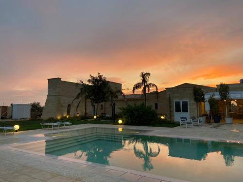 einem Pool vor einem Gebäude mit Sonnenuntergang in der Unterkunft PODERE CARAFA in Nardò