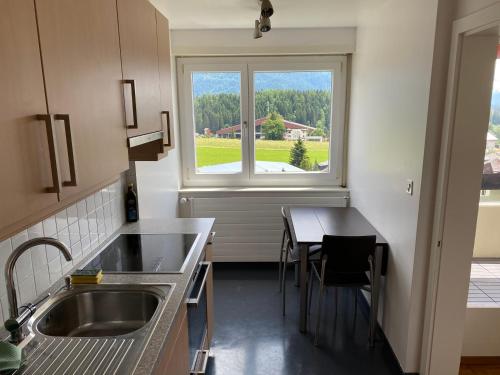 a kitchen with a sink and a table and a window at Swiss Mountains in Leysin