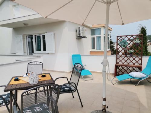 een patio met een tafel en stoelen en een parasol bij Apartments Relax Punat in Punat