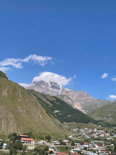 a snow covered mountain with a town in the foreground at Soso Burduli's Guesthouse in Stepantsminda