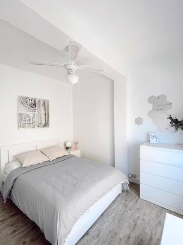 a white bedroom with a bed and a ceiling fan at Sweet apartment in Calafell