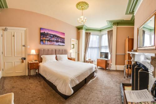 a bedroom with a large bed and a fireplace at Pannett House Bed & Breakfast, Beautiful Victorian residence in Whitby