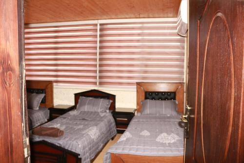 two beds in a small room with a window at Basant Villa in Wadi Musa