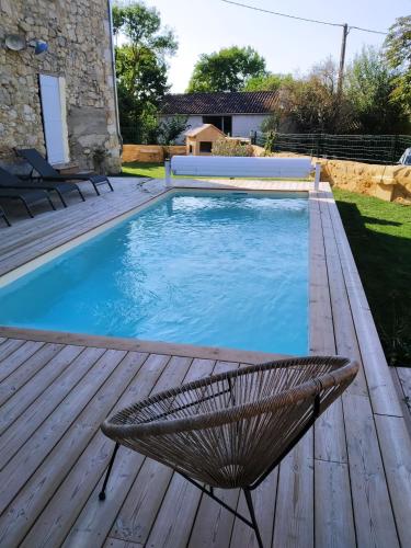a swimming pool with a chair on a wooden deck at Gîte Moishan in Mouchan