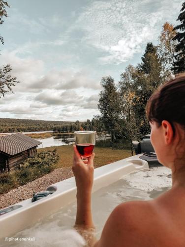 a woman sitting in a bath tub holding a glass of wine at Ollero Eco Lodge (including a glass igloo) in Rovaniemi