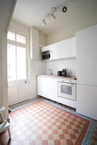 - une cuisine avec des placards blancs et un sol en damier dans l'établissement Villa Henriette - Confort et style 1900 à deux pas de la plage, au Tréport