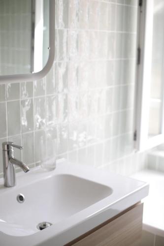 une salle de bain blanche avec un lavabo et un miroir dans l'établissement Villa Henriette - Confort et style 1900 à deux pas de la plage, au Tréport