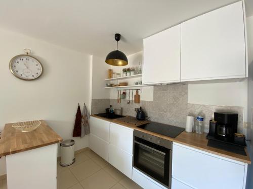 une cuisine avec des placards blancs et une horloge murale dans l'établissement Escapade méditerranéenne, à La Seyne-sur-Mer