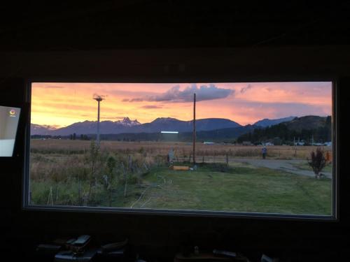 a window with a view of a field and mountains at Los Tres Picos in Cholila