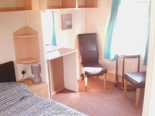 a bedroom with a bed and a sink and two chairs at Cosy Chalet Mobile Home in Dingle